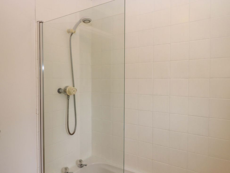 A shower area with a glass panel and a bathtub at Hedgehogs Barnstaple