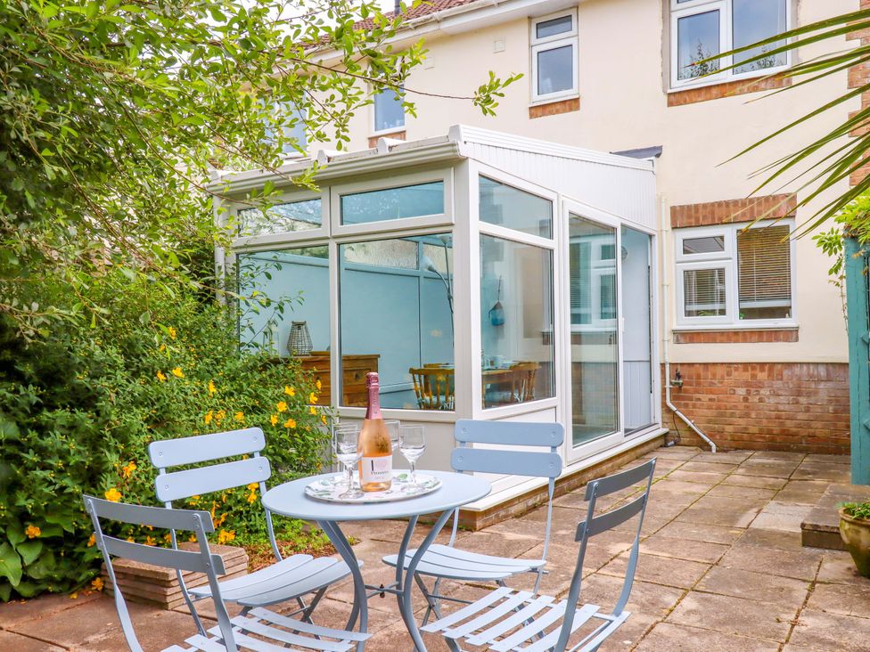 A garden with a table and chairs near a conservatory at Hedgehogs Barnstaple