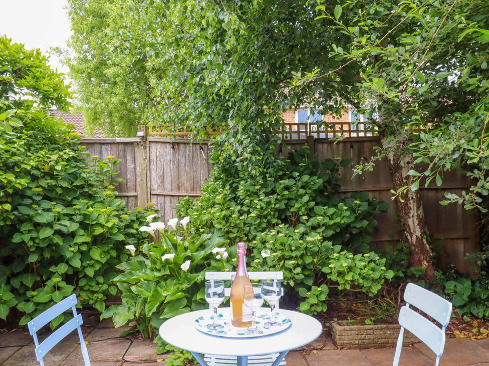 A garden with a table, chairs, a bottle, and glasses at Hedgehogs in Barnstaple