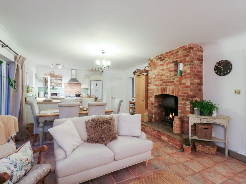 A living room with a fireplace and table at Berkley Cottage in Colchester