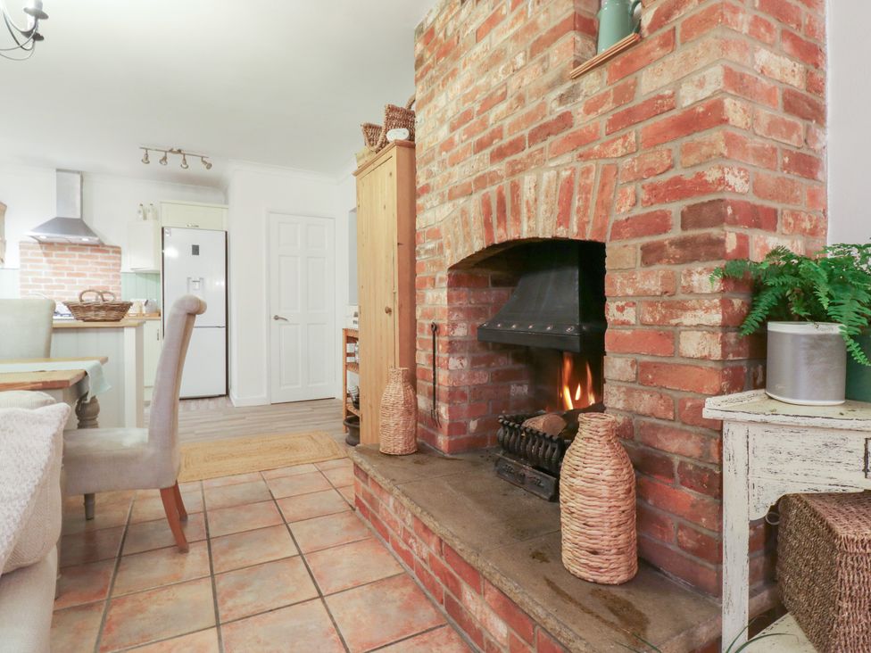 A kitchen with a fireplace and dining table at Berkley Cottage in Colchester