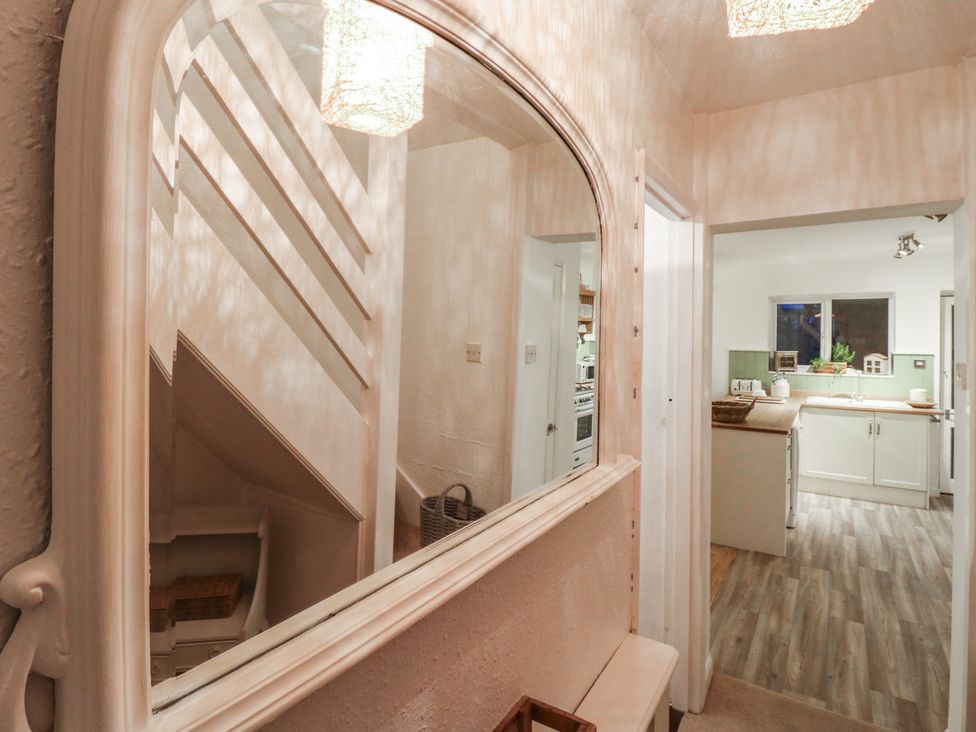 A hallway with a staircase and a view into the kitchen at Berkley Cottage in Colchester