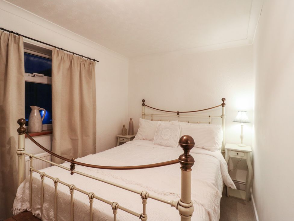 A bedroom with a bed and nightstand at Berkley Cottage in Colchester