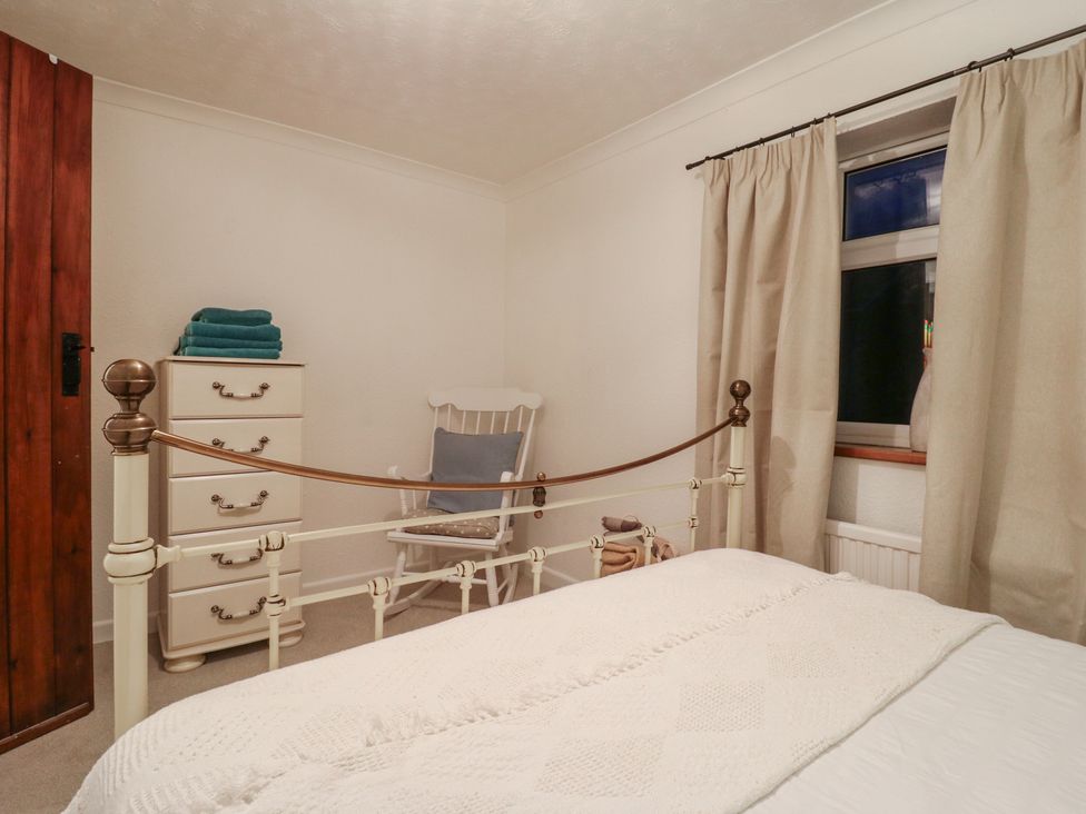 A bedroom with a bed and rocking chair at Berkley Cottage in Colchester