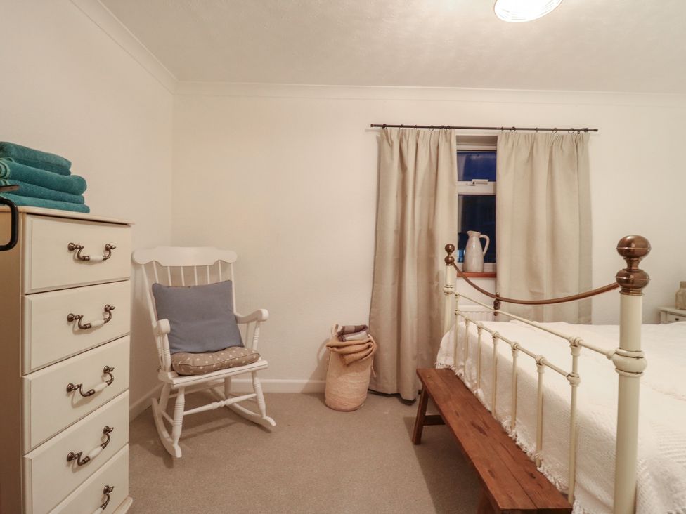 A bedroom with a bed and a rocking chair at Berkley Cottage in Colchester