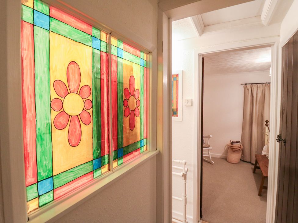 A hallway with a stained glass window and a visible room with furniture at Berkley Cottage in Colchester