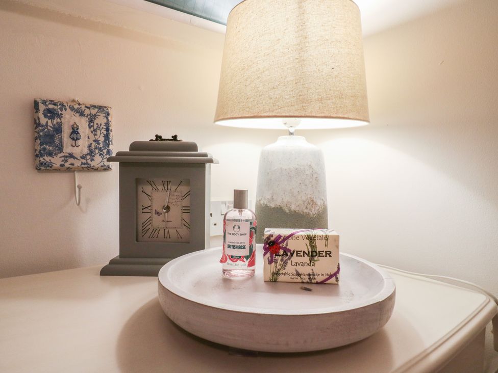 A table with a clock and lamp at Berkley Cottage in Colchester