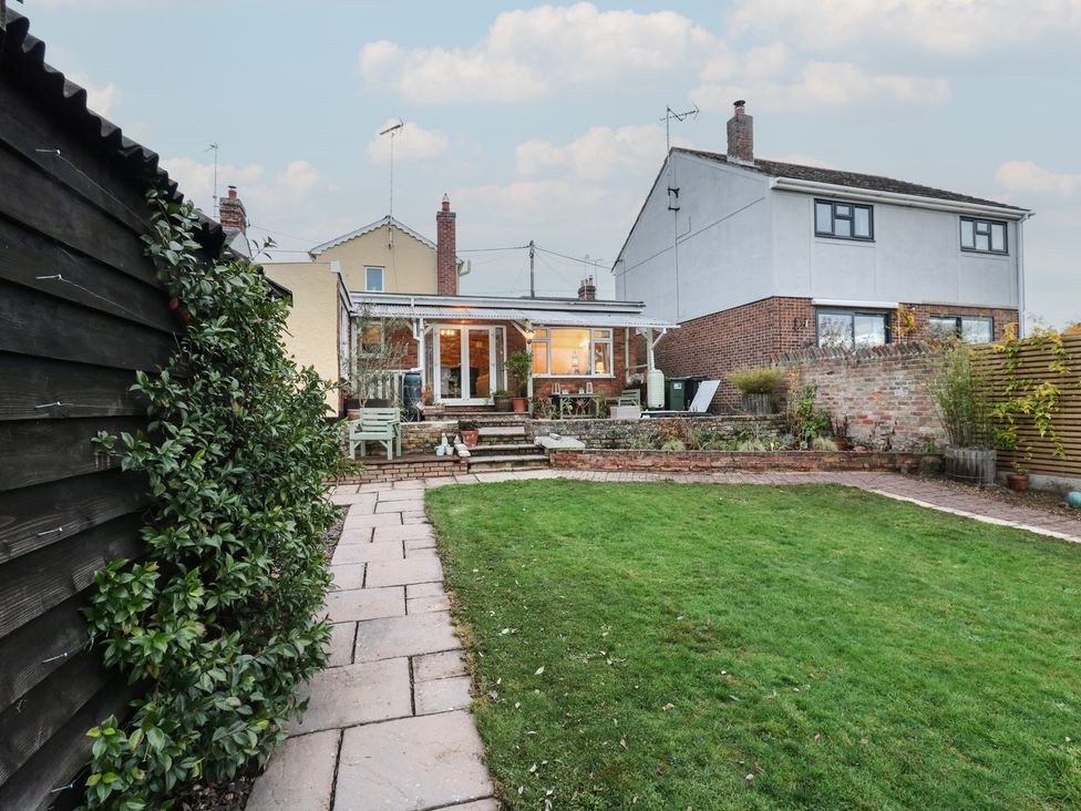 A garden with a patio and steps leading to the house at Berkley Cottage in Colchester