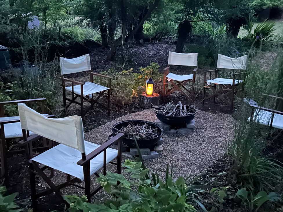 A garden seating area with chairs and a fire pit at Berkley Cottage in Coggeshall