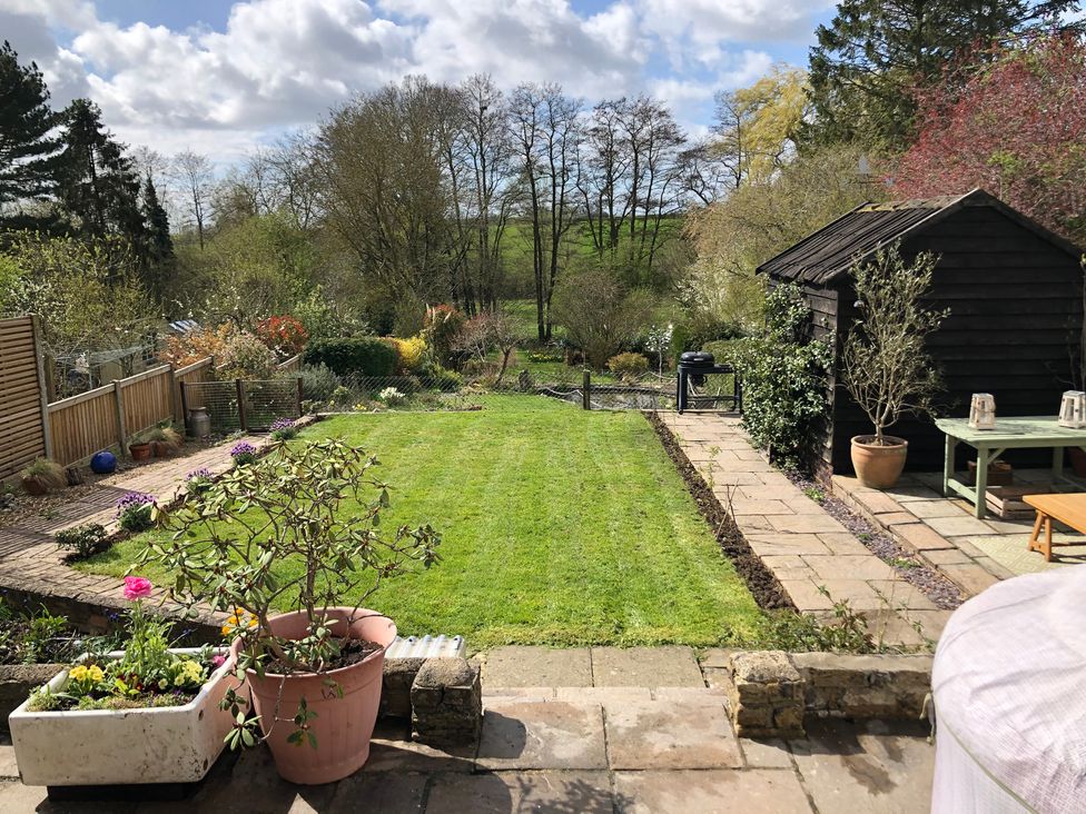 A garden with grass and flower pots at Berkley Cottage in Coggeshall