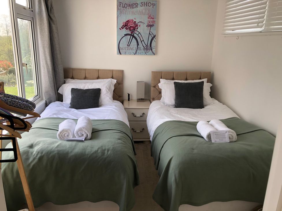 A bedroom with two beds and wall art at Berkley Cottage in Coggeshall