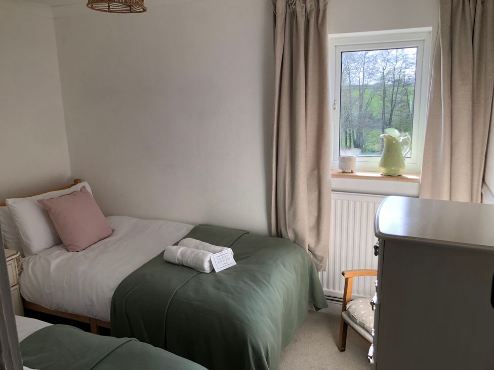 A bedroom with two single beds and a window at Berkley Cottage, Coggeshall