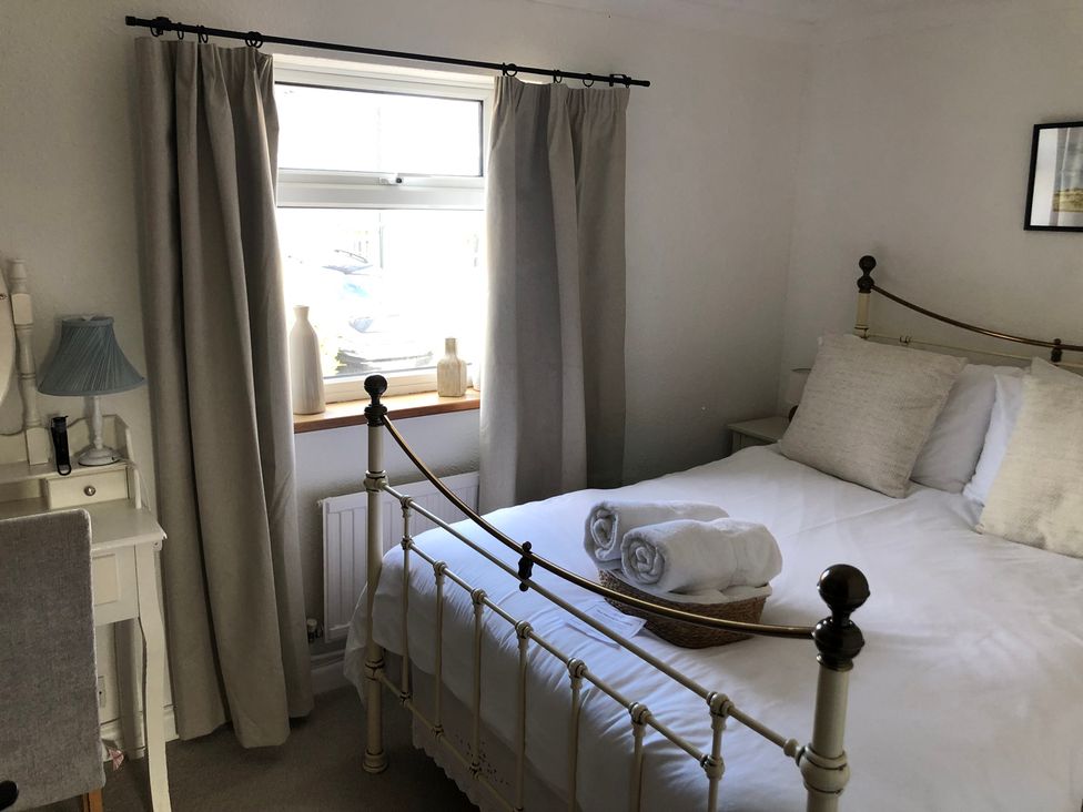 A bedroom with a bed and a window at Berkley Cottage in Coggeshall