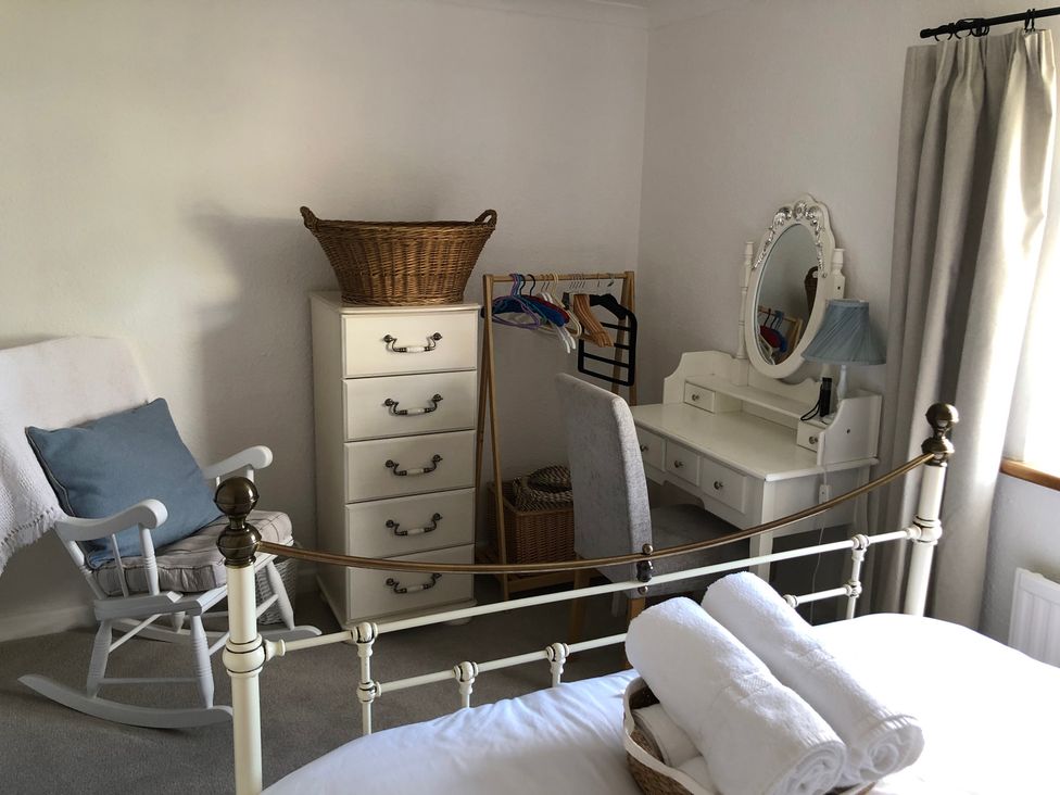 A bedroom with a bed and a vanity table at Berkley Cottage in Coggeshall