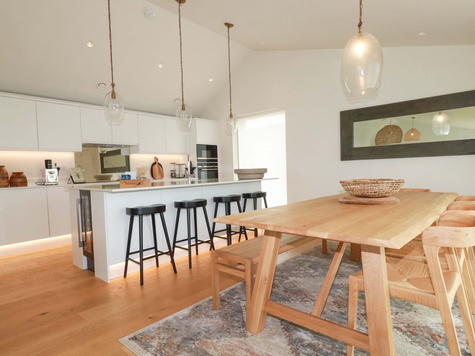 A kitchen with a dining table and bar stools at 8 Karn Havos St. Eval near Mawgan Porth