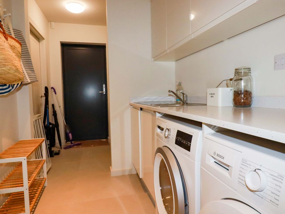 A laundry room with a washing machine, dryer, and sink at 8 Karn Havos in St. Eval near Mawgan Porth