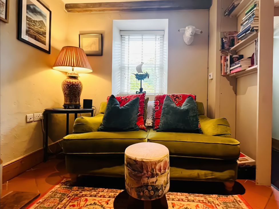 A living room with a green sofa and lamp at Copper Miners Cottage, Beddgelert, Eryri (snowdonia)