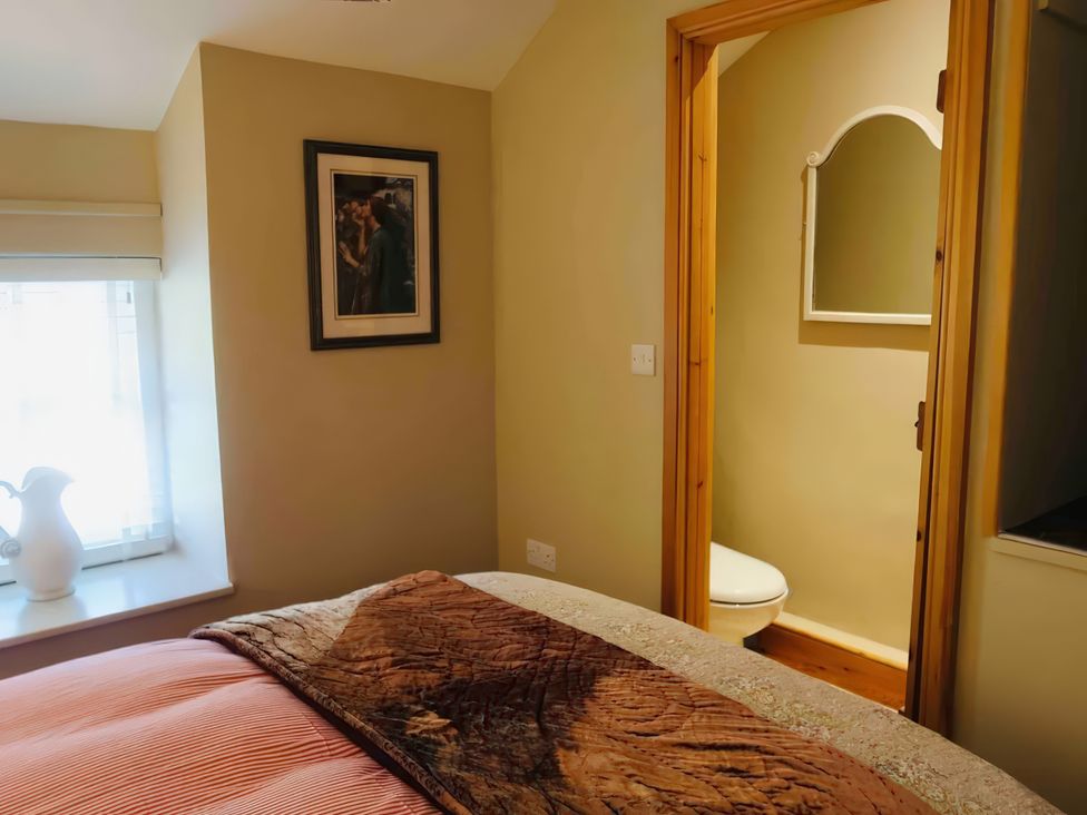 A bedroom with a bed and doorway leading to a toilet at Copper Miners Cottage, Beddgelert, Eryri (snowdonia)