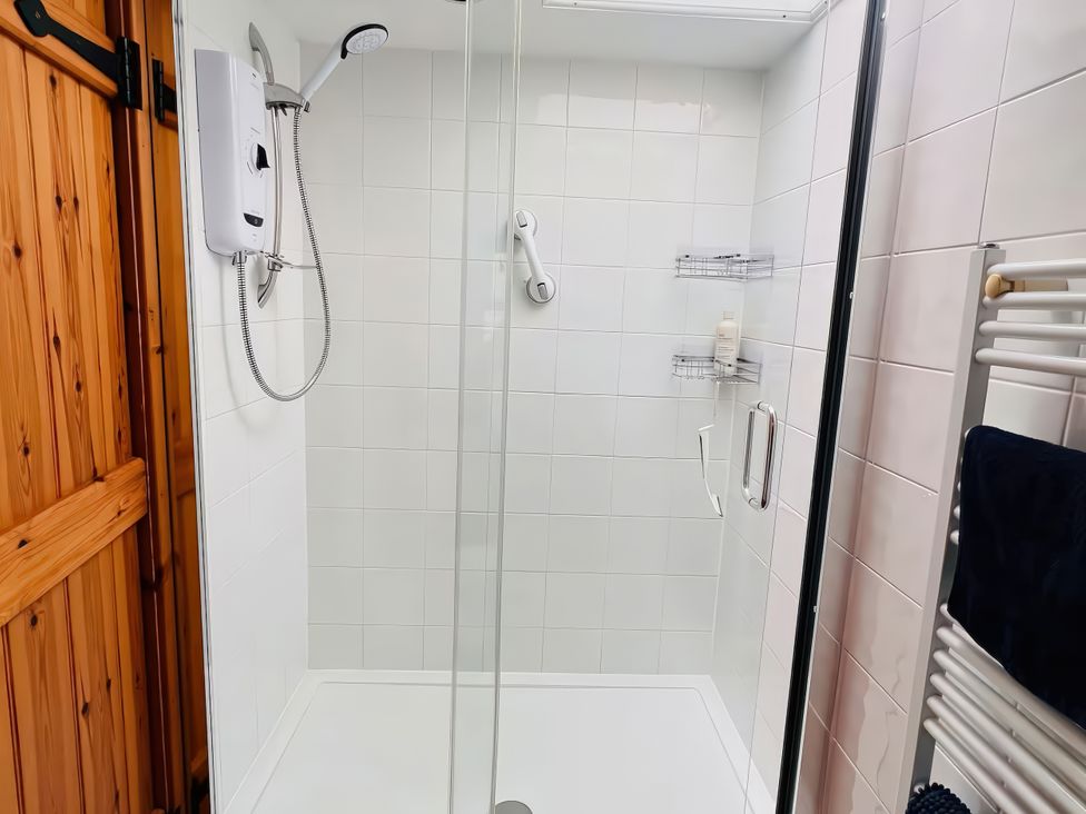A shower with glass door and wall shelf at Copper Miners Cottage, Beddgelert, Eryri (snowdonia)