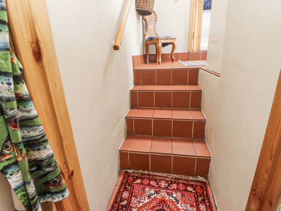A staircase with a rug and chair at Copper Miners Cottage in Beddgelert, Eryri (snowdonia)