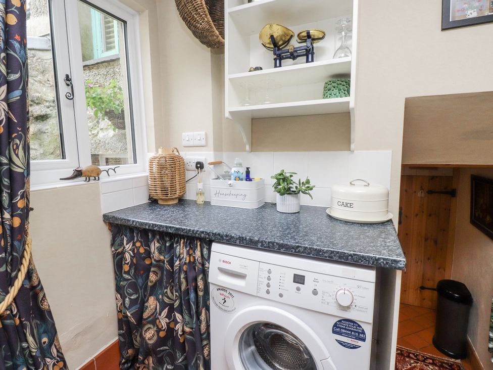 A utility room with a washing machine and counter at Copper Miners Cottage, Beddgelert, Eryri (snowdonia)