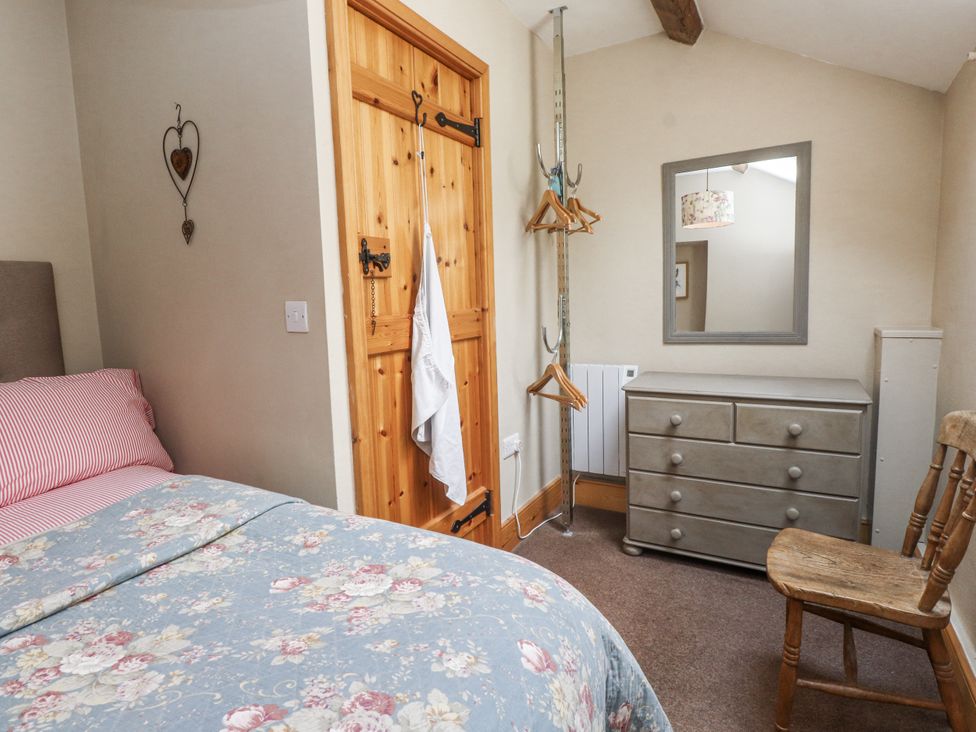 A bedroom with a bed, dresser, mirror, and chair at Copper Miners Cottage, Beddgelert, Eryri (snowdonia)