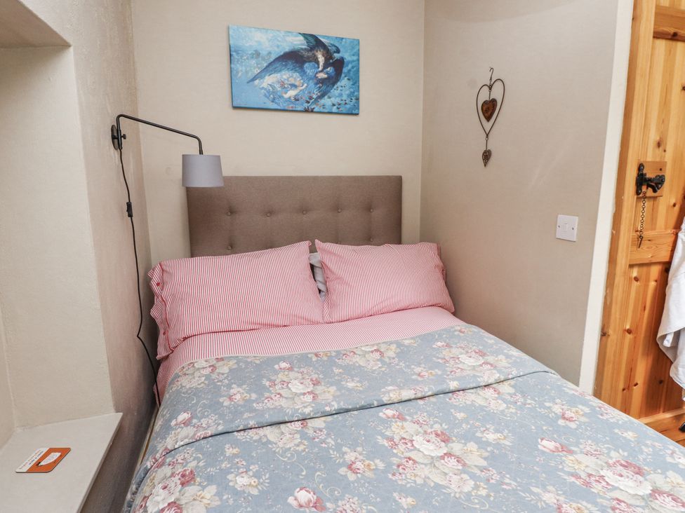 A bedroom with a bed and artwork at Copper Miners Cottage in Beddgelert, Eryri (snowdonia)