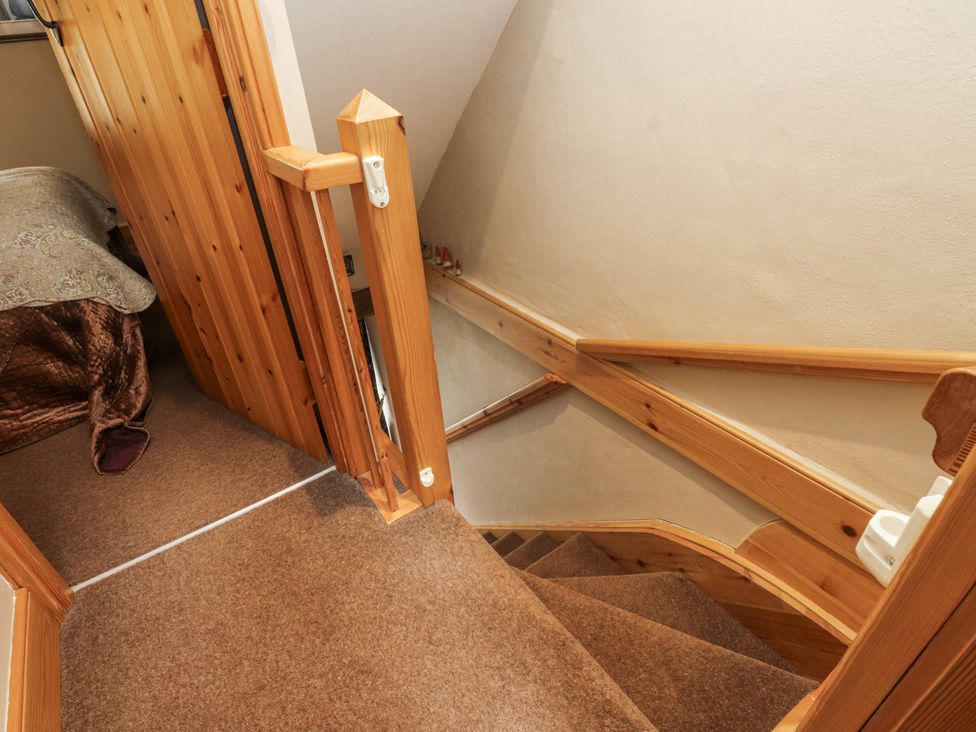 Staircase with wooden handrail and door at Copper Miners Cottage, Beddgelert, Eryri (snowdonia)