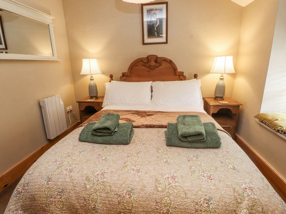 A bedroom with a bed and bedside tables at Copper Miners Cottage, Beddgelert, Eryri (snowdonia)