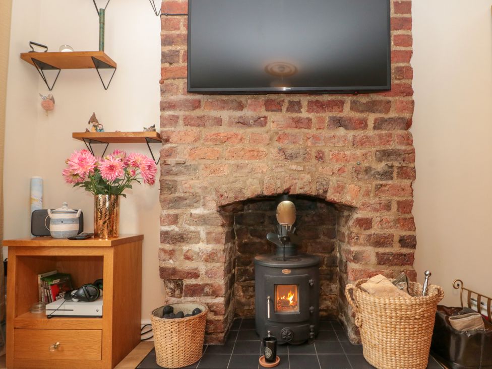 A living room with a wood stove and television at No.64 Nelson St in Bridlington