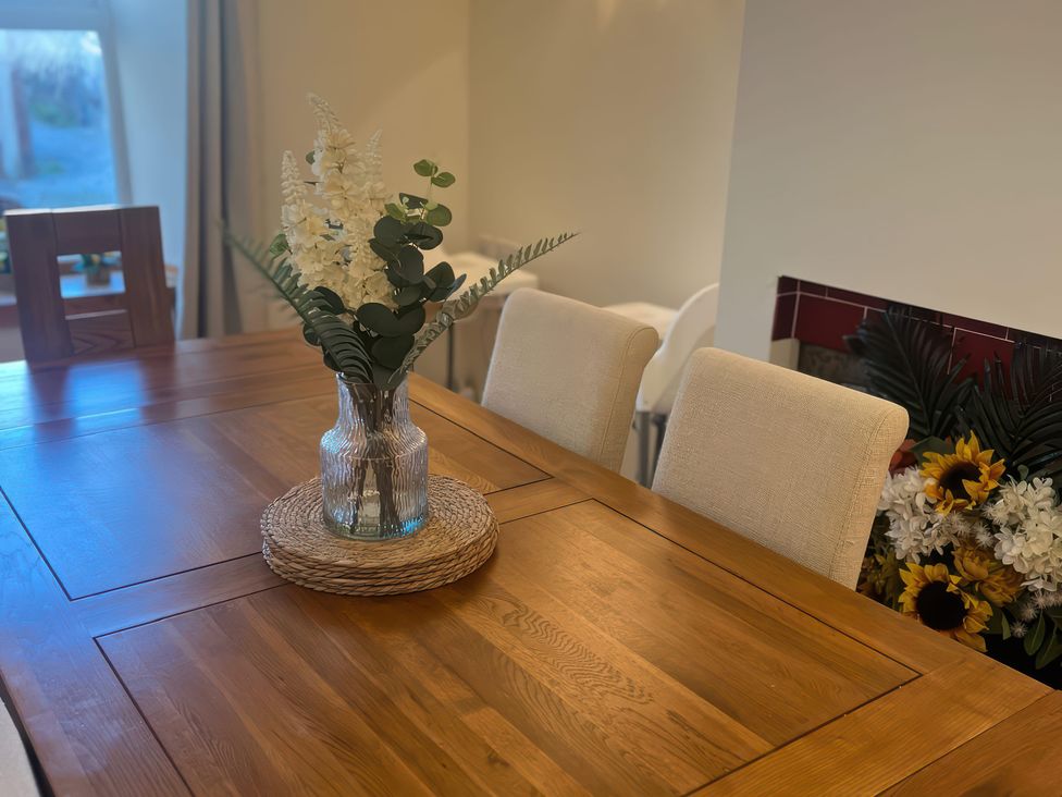 A dining table with a vase and flowers at Sun House in Allonby