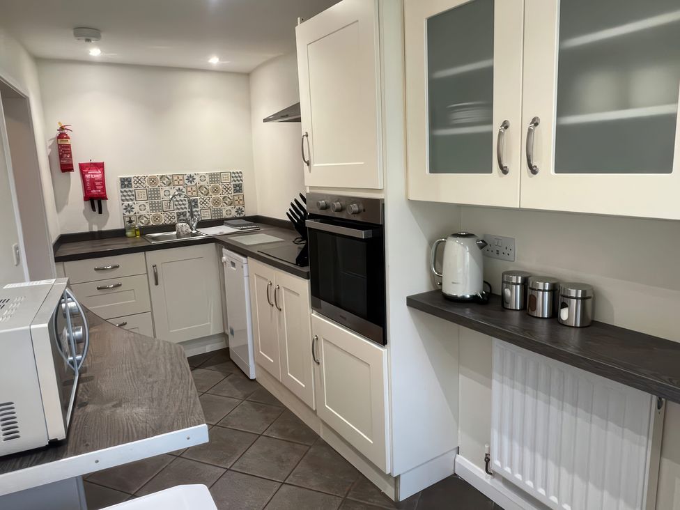 A kitchen with microwave, oven, kettle, and sink at Sun House in Allonby