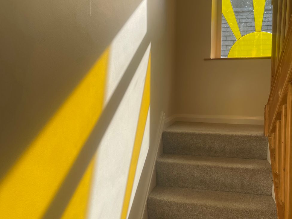 A staircase with sunlight coming through a window at Sun House in Allonby