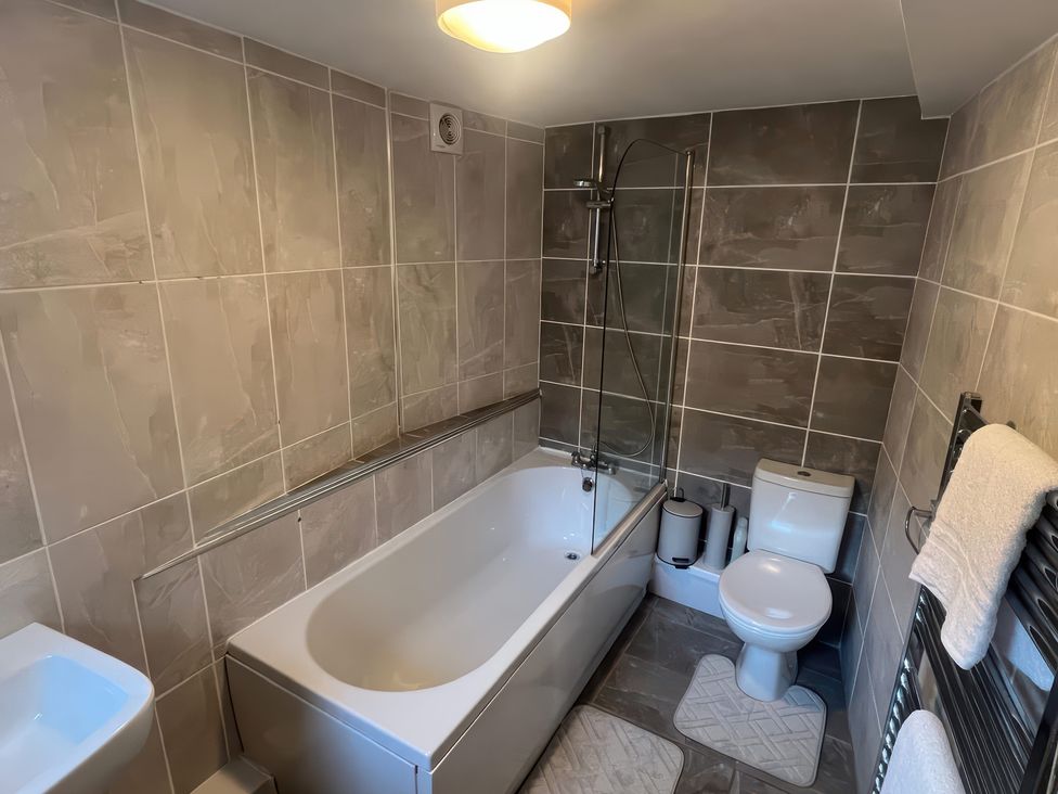 A bathroom with a bathtub, toilet, and sink at Sun House in Allonby