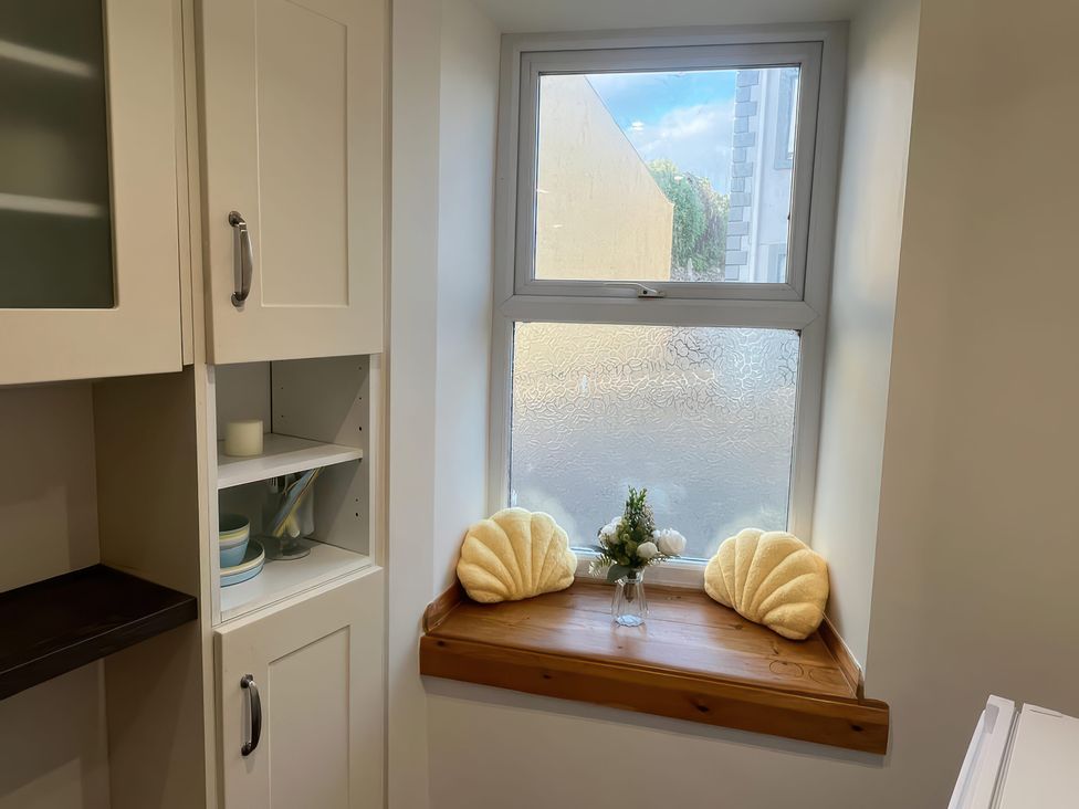 A kitchen with a window and shelf containing dishes at Sun House in Allonby