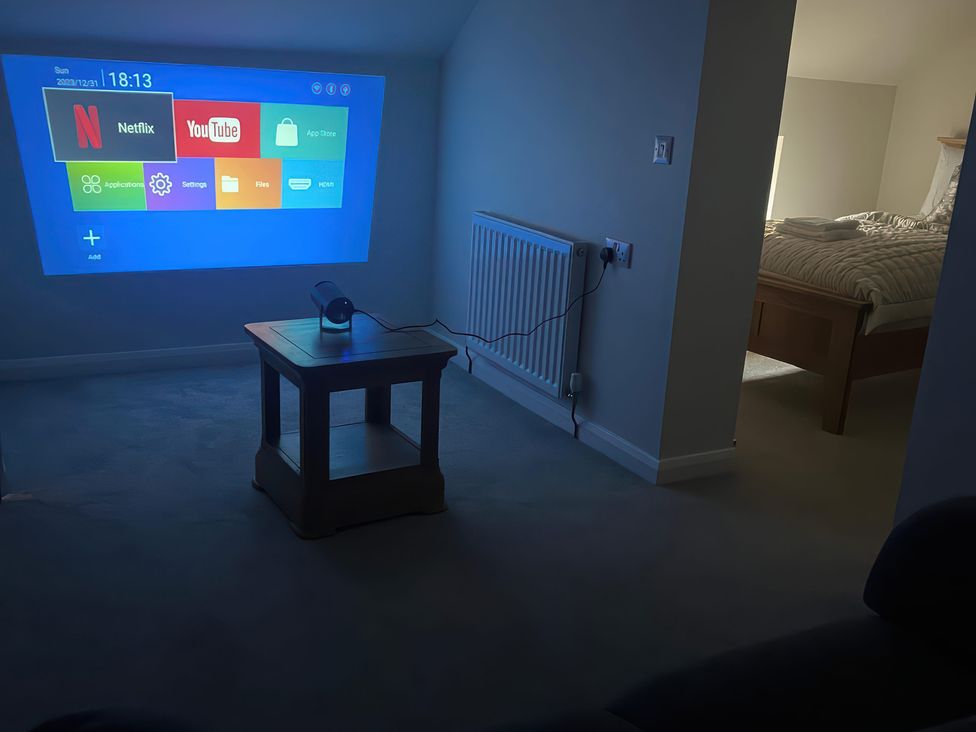 A living room with a projector display and table at Sun House in Allonby