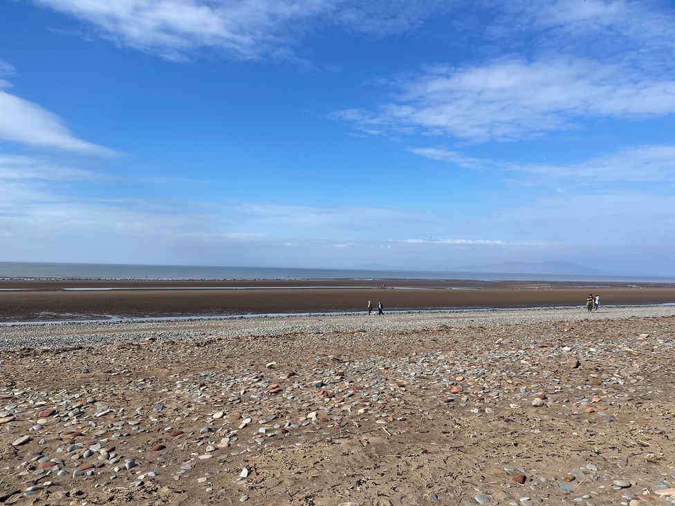 A beach with pebbles and people walking at Sun House in Allonby