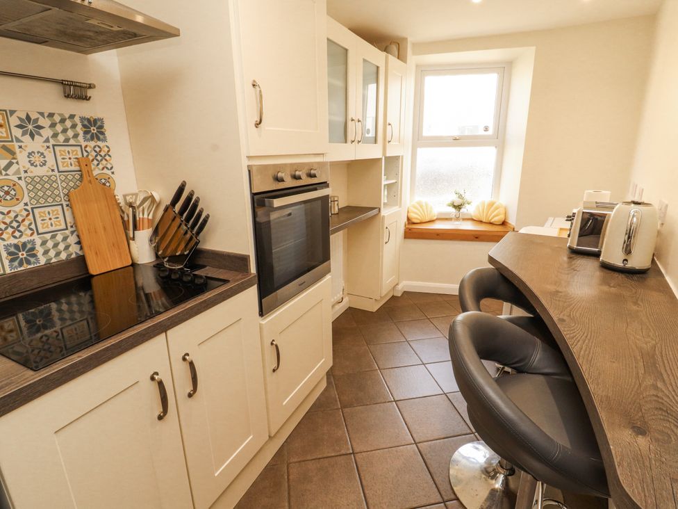 A kitchen with appliances and bar seating at Sun House in Allonby