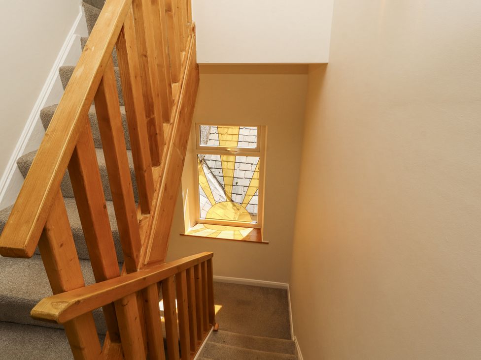A stairway with wooden railing and stained glass window at Sun House in Allonby