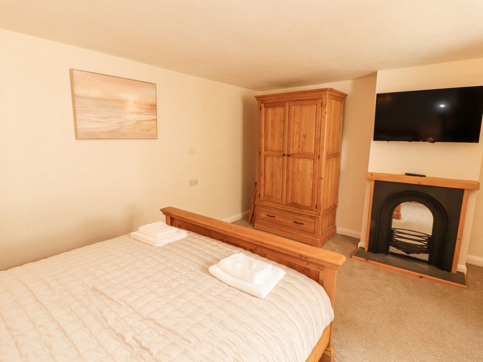 A bedroom with a bed and wooden wardrobe at Sun House Allonby