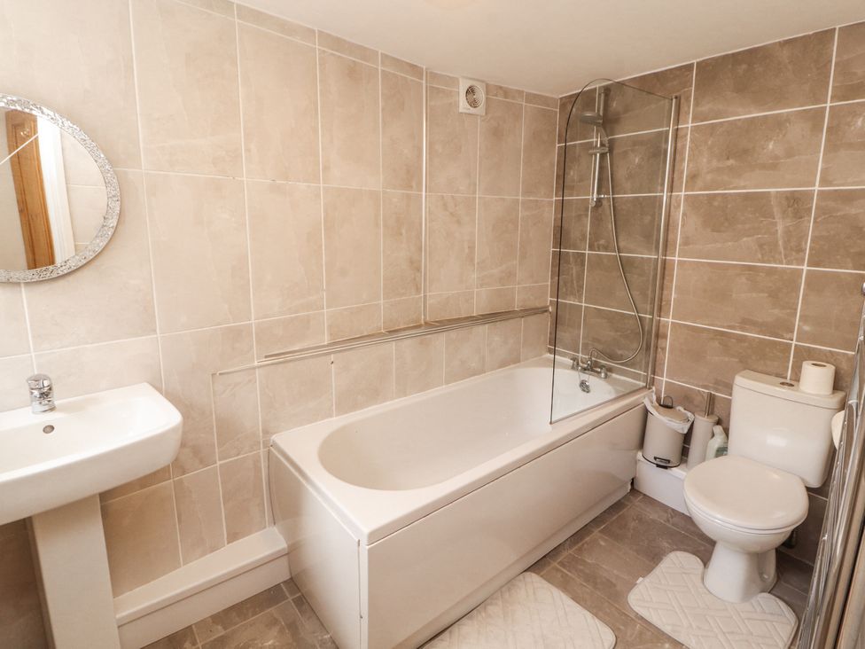 A bathroom featuring a bathtub, toilet, sink, and mirror at Sun House in Allonby