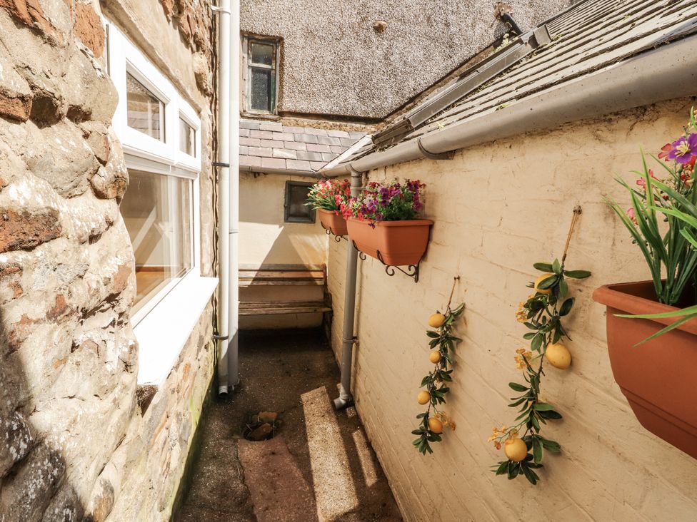An outdoor area with a stone wall and planters at Sun House in Allonby