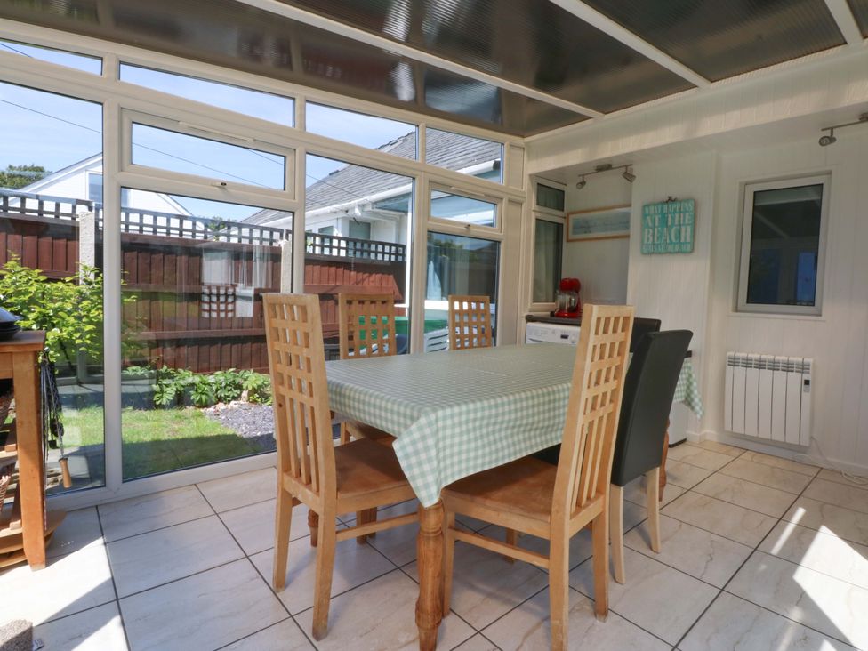 A conservatory with a dining table and chairs at Swn Y Don