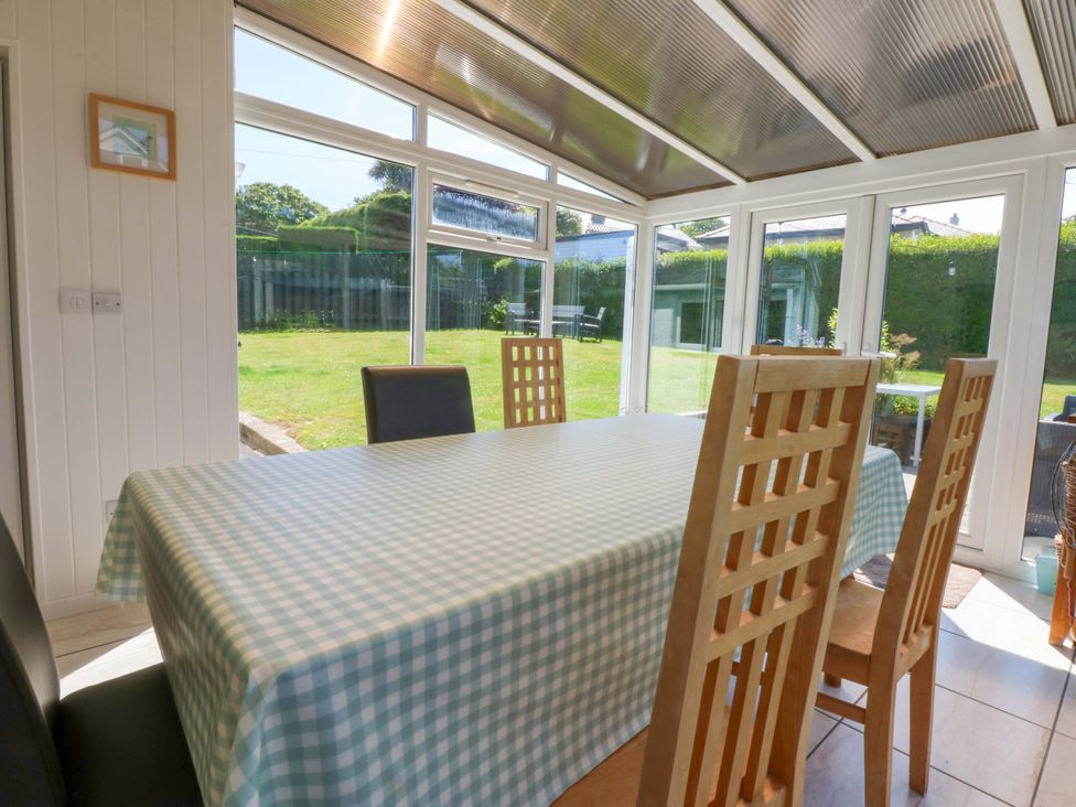 A conservatory with a table and chairs overlooking the garden at Swn Y Don
