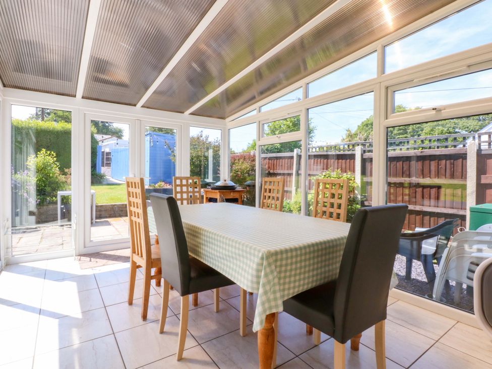 A dining table with chairs in a conservatory at Swn Y Don in 