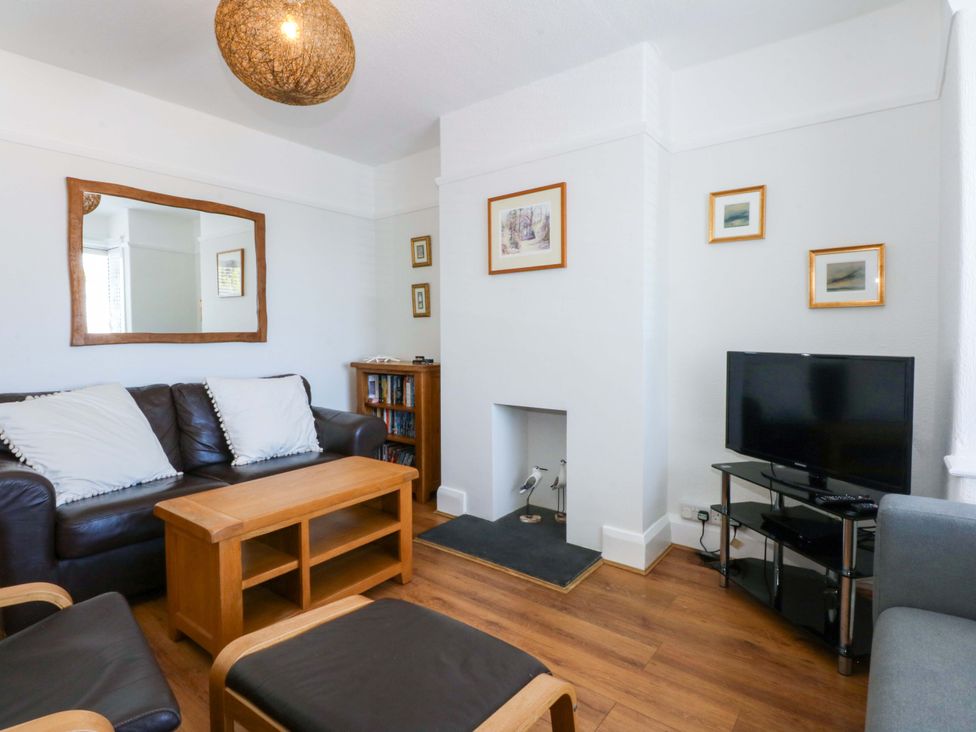 A living room with a coffee table and television at Swn Y Don