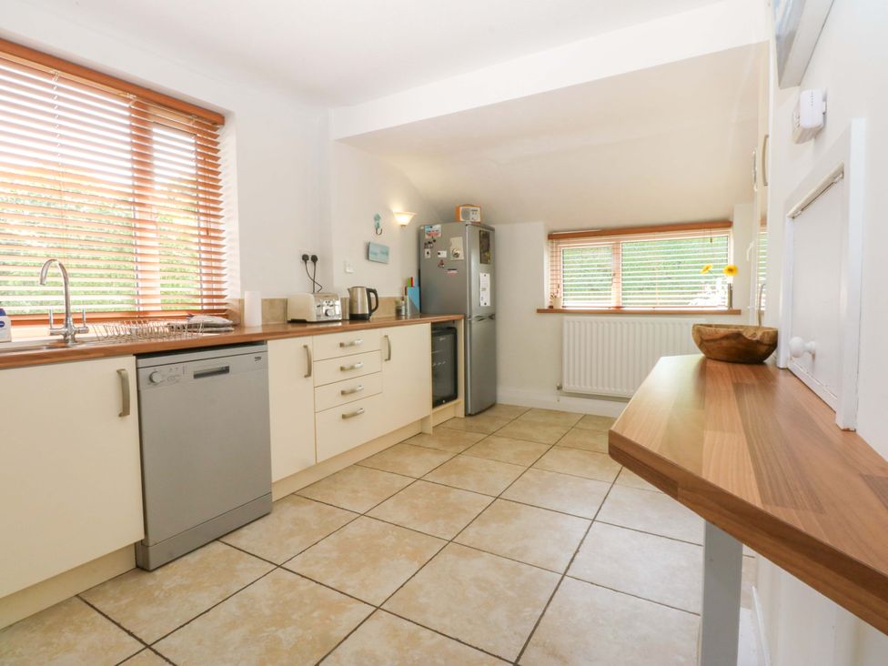 A kitchen featuring a dishwasher, sink, and refrigerator at Swn Y Don