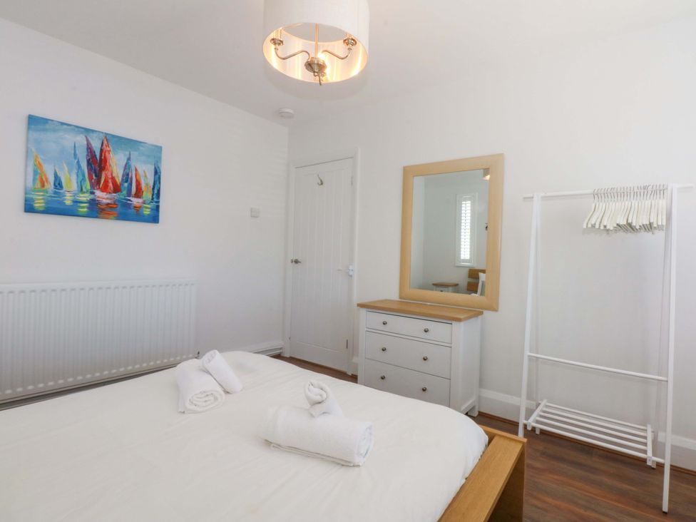 A bedroom with a bed, mirror, dresser, and wardrobe at Swn Y Don