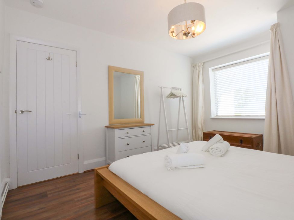 A bedroom with a bed, mirror, and dresser at Swn Y Don