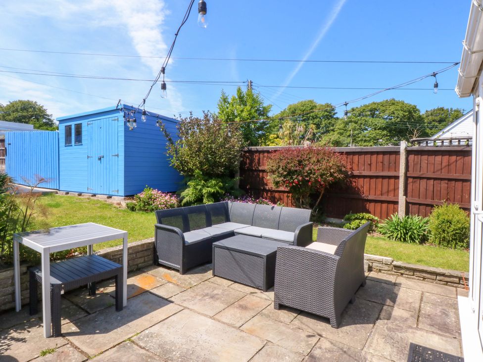 A garden with seating area and a blue shed at Swn Y Don